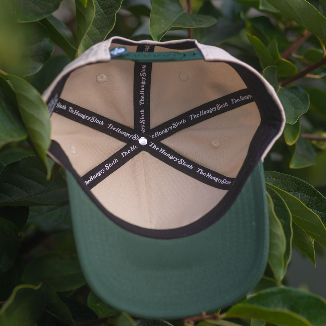 natural and green snapback hat with the hungry sloth branding underneath
