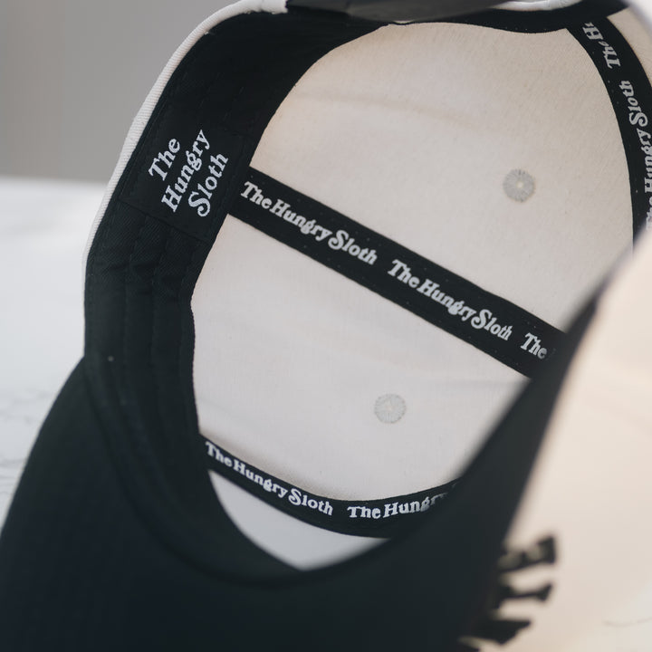 Close-up of the inside of an off-white snapback hat with the logo &