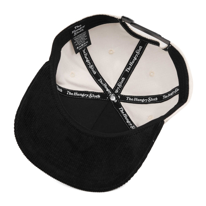 white and black corduroy snapback hat with the hungry sloth branding underneath