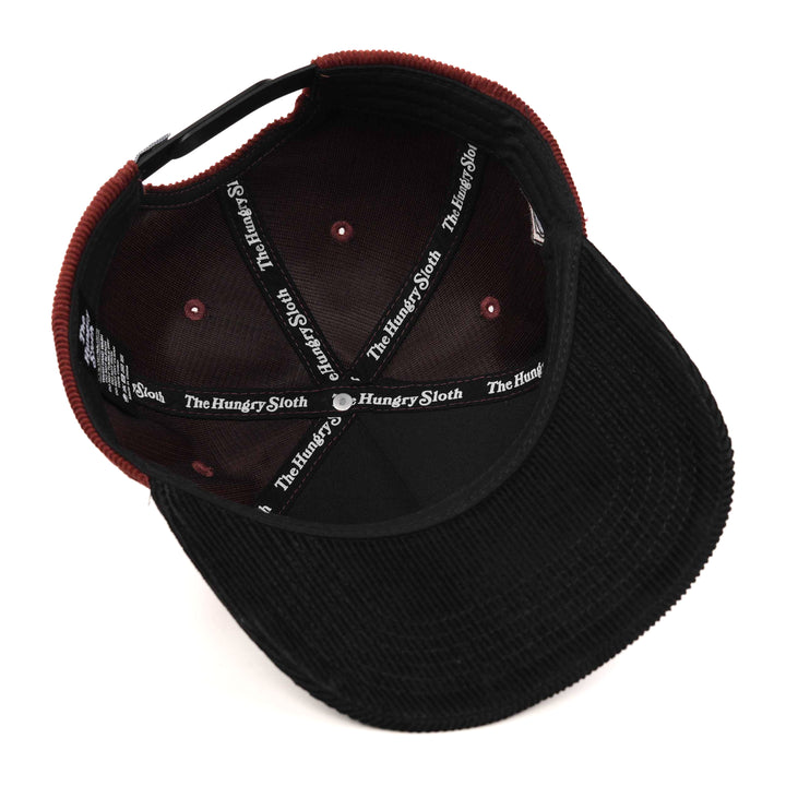 maroon corduroy snapback hat with black undervisor and the hungry sloth branding underneath